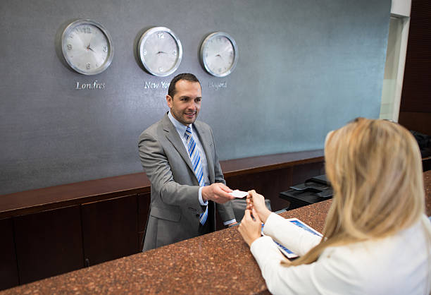 Happy woman doing check in at a hotel and paying by credit card