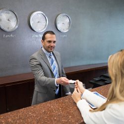 Happy woman doing check in at a hotel and paying by credit card
