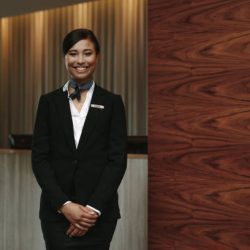 Portrait of happy female hotel receptionist standing at workplace. Smiling woman receptionist working in hotel.
